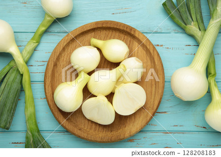 Green onion on wooden plate on blue wooden background. Green onion on wooden plate on blue wooden background. 128208183