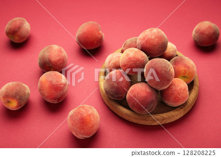 Sweet peaches and leaves on wooden plate on red background. Space for text Sweet peaches and leaves on wooden plate on red background. Space for text 128208225