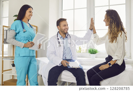 Doctor giving high five with a young happy woman patient in medical clinic. 128208785