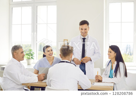Group of happy doctors in a clinic sitting together at a table, close-up 128208786