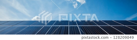 Solar panels under a clear blue sky, capturing sunlight. Concept of renewable energy and sustainability. For energy and environment-related projects. 128209849