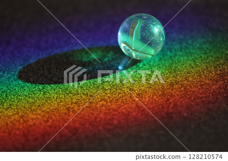 Small, clear, round ball sits on a dark surface Small, clear, round ball sits on a dark surface 128210574