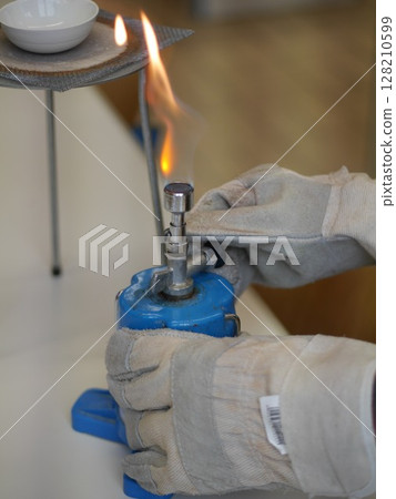 Person is holding a blue object with a flame on it 128210599