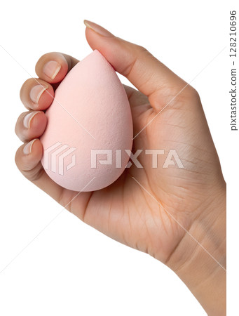 Hand holding soft pink makeup sponge isolated on transparent background, beauty blender, cosmetic tool, flawless foundation application 128210696