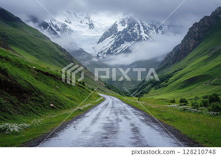 A country road among green hills leading to the foot of a mountain on a cloudy day. Generated by artificial intelligence 128210748