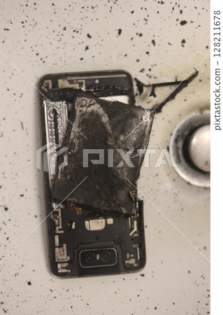 Phone is on a sink with a burnt battery 128211678