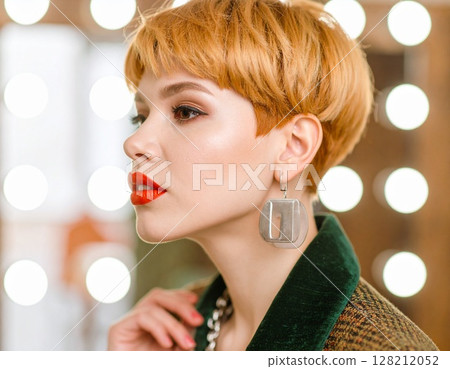 戴著令人印象深刻的耳環的女人的側面肖像（短髮，工作室拍攝） 128212052