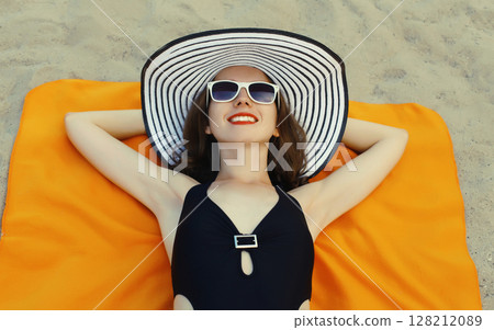 Summer vacation, beautiful happy relaxing young woman in swimsuit lying on sand on the beach 128212089