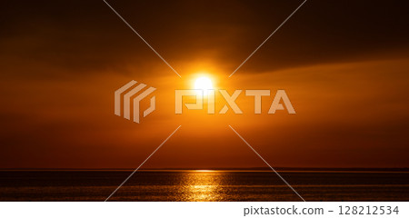 Beautiful sunset over the sea. The sun is setting on the water. The sky is painted with bright colors. Summer evening at sunset beach. Underexposed dawn photography. Horizontal banner background. Beautiful sunset over the sea. The sun is setting on the water. The sky is painted with bright colors. Summer evening at sunset beach. Underexposed dawn photography. Horizontal banner background. 128212534