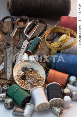 Sewing needles stuck in a green miniature spools thread Steel scissors, Spools of thread of various colour, Thimbles and Measuring tape including Pins and Buttons in small round tray. 128212656
