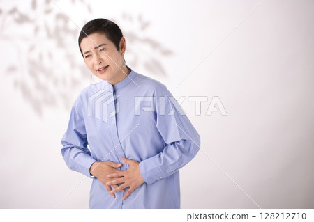 Middle-aged woman grimacing with stomach pain 128212710