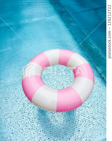 Swimming ring with pink and white stripes in a blue outdoor pool. Poolside atmosphere. Pink float. 128212722