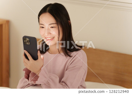 A woman looking at her smartphone in the middle of the night 128212940