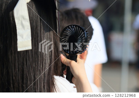 Woman walking with a handheld fan Portable fan Woman walking with a handheld fan Portable fan 128212968