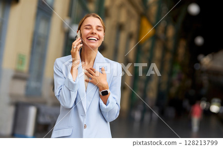 A Joyful Businesswoman Engaged in a Friendly Conversation on Her Phone in an Urban Setting A Joyful Businesswoman Engaged in a Friendly Conversation on Her Phone in an Urban Setting 128213799