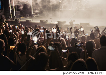 Audience holding up cell phones to record event 128214490