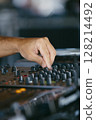 Close up view of a dj's hands playing the mixer while performing in a music festival.  128214492