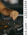 Close up view of a dj's hands playing the mixer while performing in a music festival. 128214494