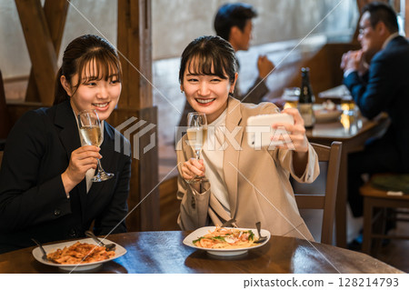 Office ladies and businesswomen taking photos with their smartphones at a girls' gathering at a restaurant, eatery, or izakaya 128214793