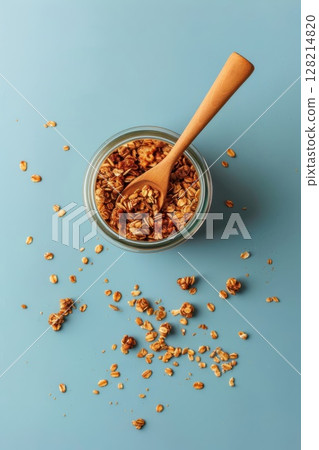 Top view of a jar of granola and a wooden spoon on a light blue background. Flat lay composition with copy space, pastel colors. Top view of a jar of granola and a wooden spoon on a light blue background. Flat lay composition with copy space, pastel colors. 128214820