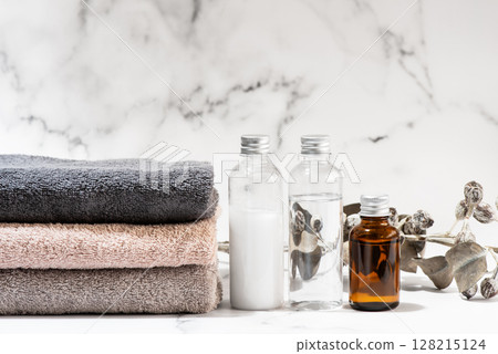 大理石背景上擺放著乾淨的毛巾、化妝品和乾燥花 128215124