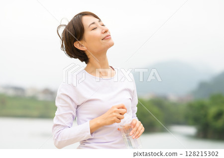 Woman hydrating in the park 128215302