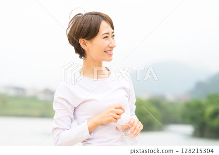 Woman hydrating in the park 128215304