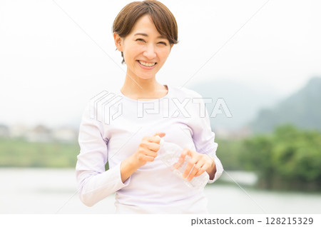 Woman hydrating in the park 128215329