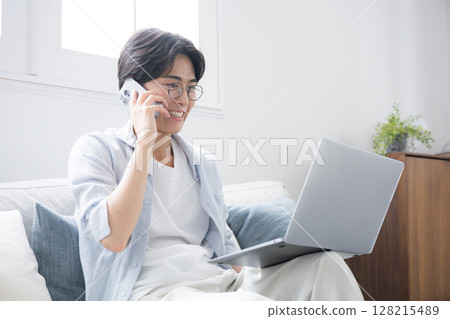 A man smiling and talking on the phone while looking at a computer. Image of a freelancer or busy office worker 128215489
