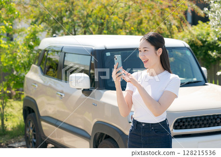 A woman in her twenties standing in front of a car 128215536