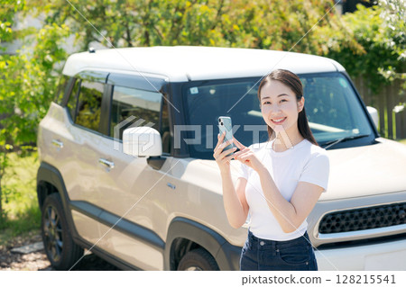 A woman in her twenties standing in front of a car 128215541