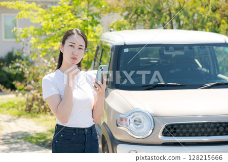 A woman in her twenties standing in front of a car 128215666