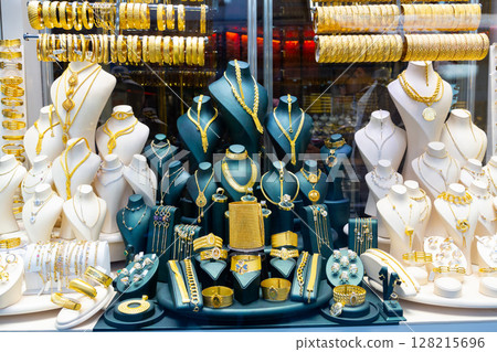 Gold jewelry at showcase of jewelry shop. Gold items in shop windows closeup Gold jewelry at showcase of jewelry shop. Gold items in shop windows closeup 128215696