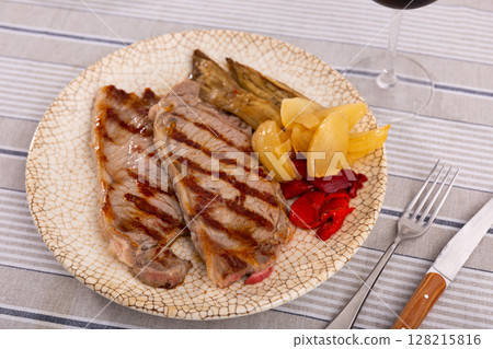 Delicious mediterranean style steak served with baked tomatoes calcot onion and tomatoes 128215816