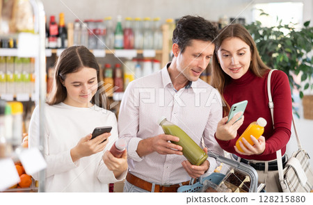 Couple of man and woman with girl scanning qr code of smoothies Couple of man and woman with girl scanning qr code of smoothies 128215880