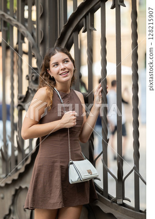 Young woman standing near the metal fence Young woman standing near the metal fence 128215907
