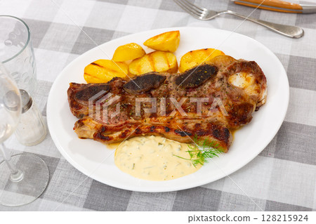 Grilled beef spare ribs with baked potatoes and sauce Grilled beef spare ribs with baked potatoes and sauce 128215924