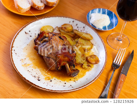 Portion of pork knuckle with boiled potatoes and gravy in plate Portion of pork knuckle with boiled potatoes and gravy in plate 128215926