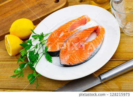 Plate with raw salmon slices, fresh parsley, garlic and lemon 128215973