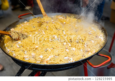 Preparation of Catalan seafood fideua in paellera on street festival 128215995