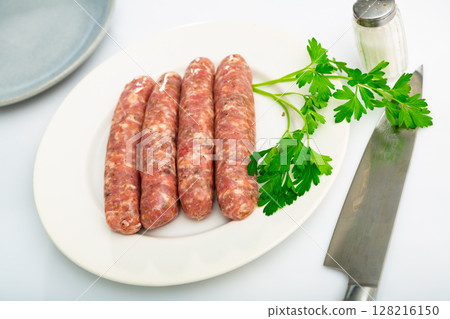 Plate with raw Catalan sausages botifarra and greens prepared for cooking 128216150