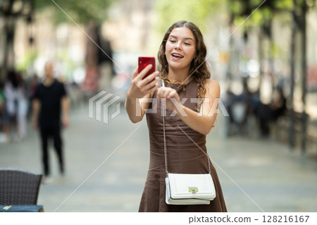woman with a phone in her hands walks around the city 128216167