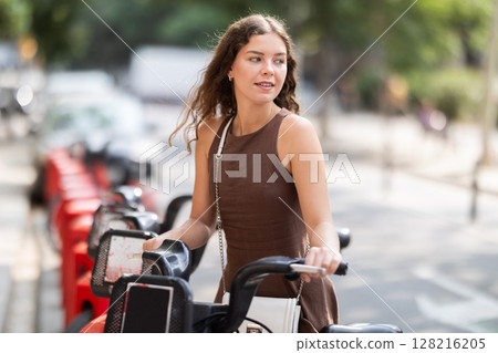 young woman stands in front of a cart of bicycles in the city 128216205
