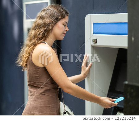 Young woman standing near ATM 128216214