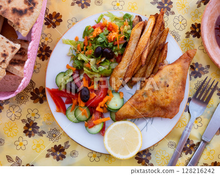 Tunisian brik pie served with vegetable salad 128216242