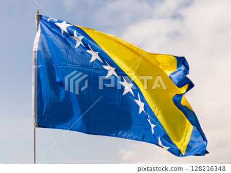 Flag of Bosnia and Herzegovina waving on cloudy sky during daytime 128216348
