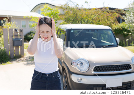 Woman holding her head next to her car Woman holding her head next to her car 128216471