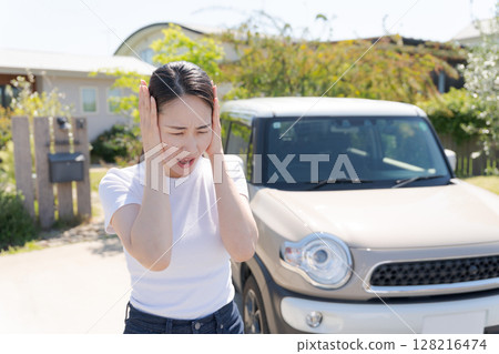 Woman holding her head next to her car Woman holding her head next to her car 128216474