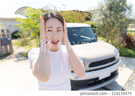 Woman holding her head next to her car Woman holding her head next to her car 128216475