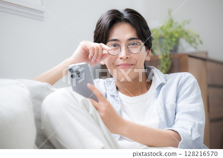 特寫鏡頭:一位英俊男子戴著眼鏡,看著智慧型手機,看著相機 特寫鏡頭:一位英俊男子戴著眼鏡,看著智慧型手機,看著相機 128216570